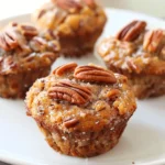 Close-up of mini pecan pie muffins topped with chopped pecans on a white plate.