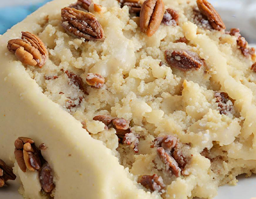 Close-up of a slice of Butter Pecan Cake with creamy frosting and pecans on top